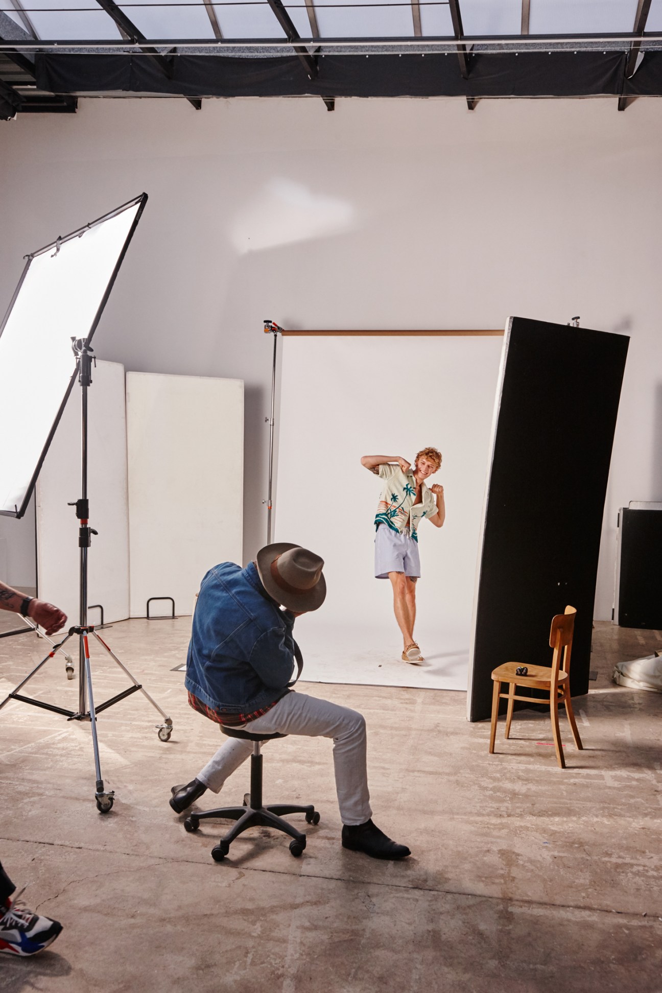 Photographer Sean Thomas shooting a young male model in a studio with professional lighting and backdrop setup.