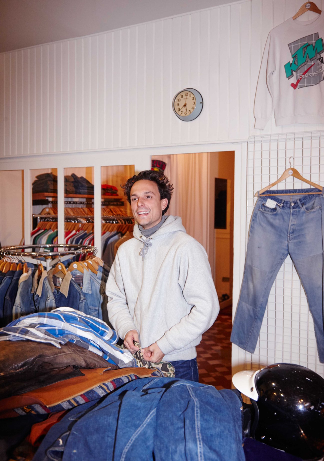 Marin Muteaud smiling in La Vif vintage shop surrounded by clothing racks and vintage denim.