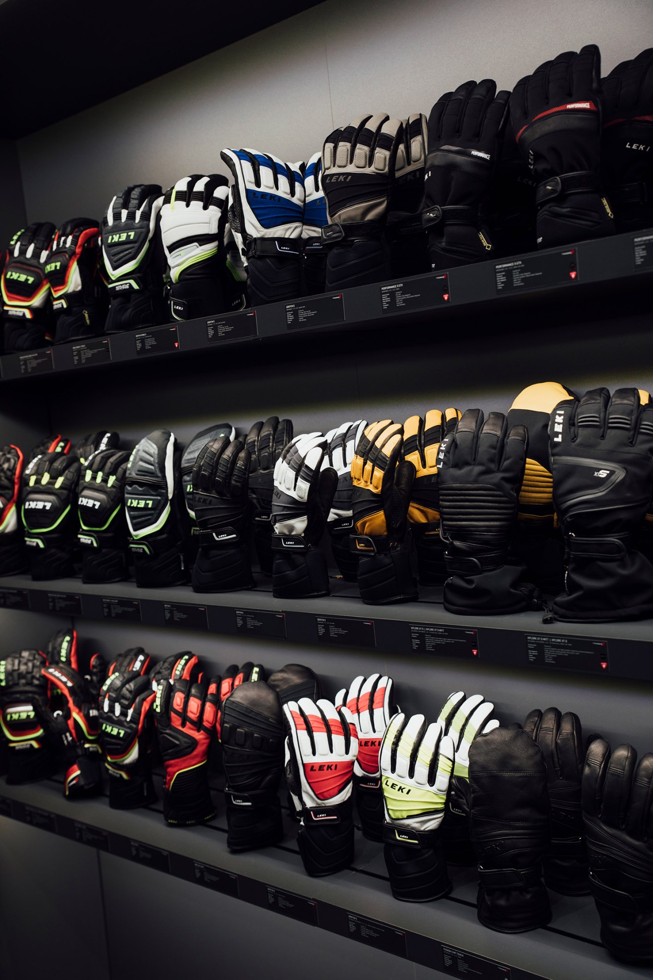 Display of Leki ski gloves on shelves showing various colors including blue, white, yellow, and black with neon accents.