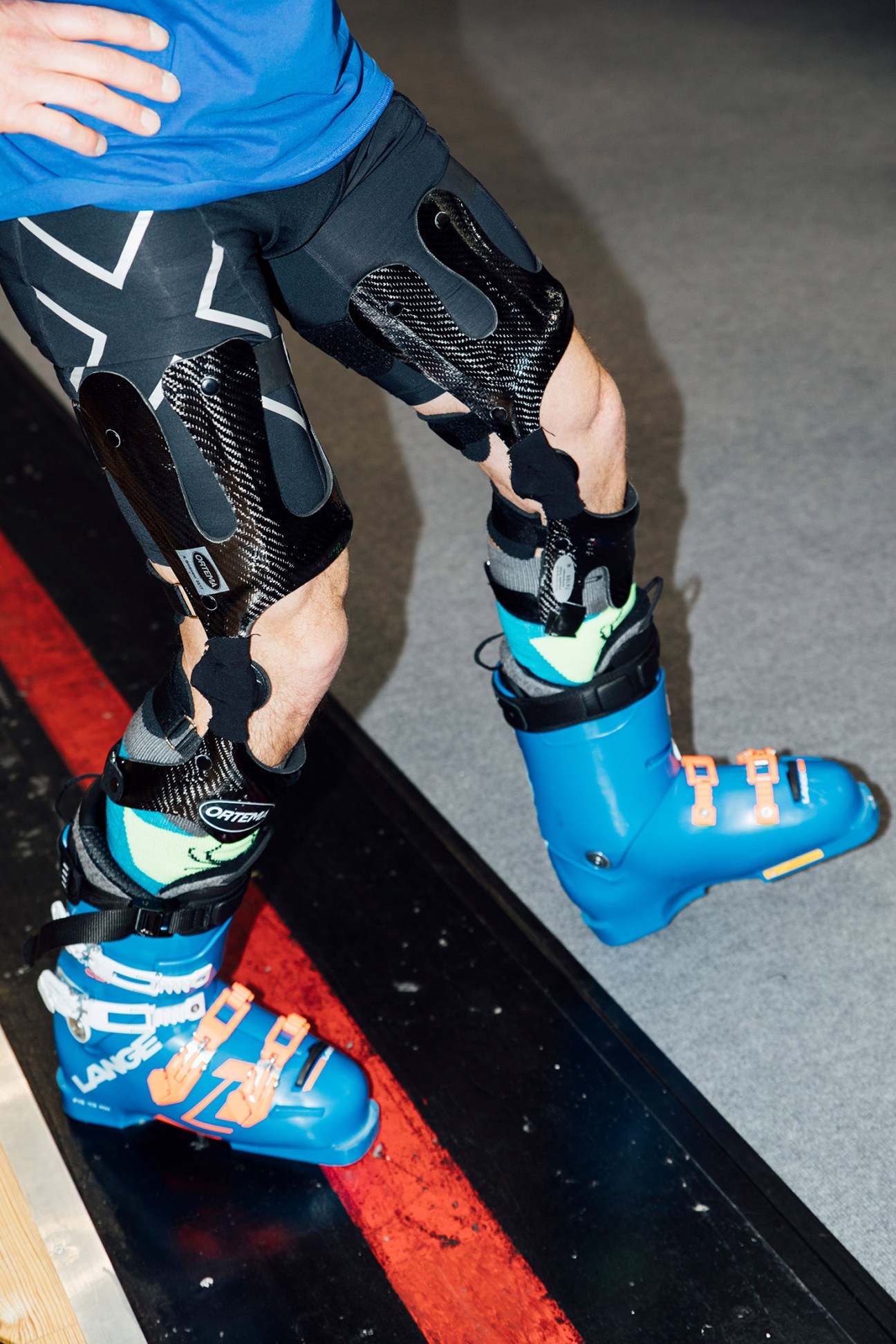 Person wearing blue ski boots and black athletic leggings with white geometric patterns.