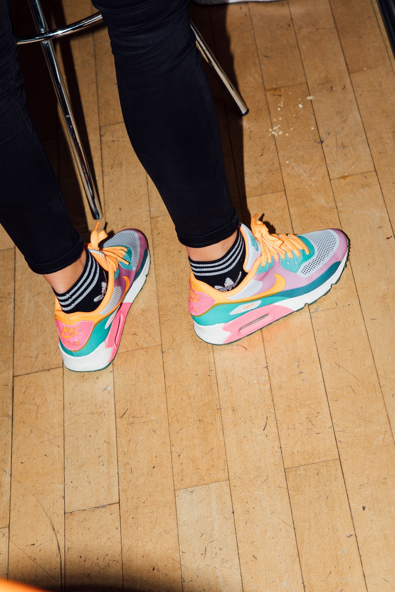 Colorful Nike running shoes with striped socks on wooden floor