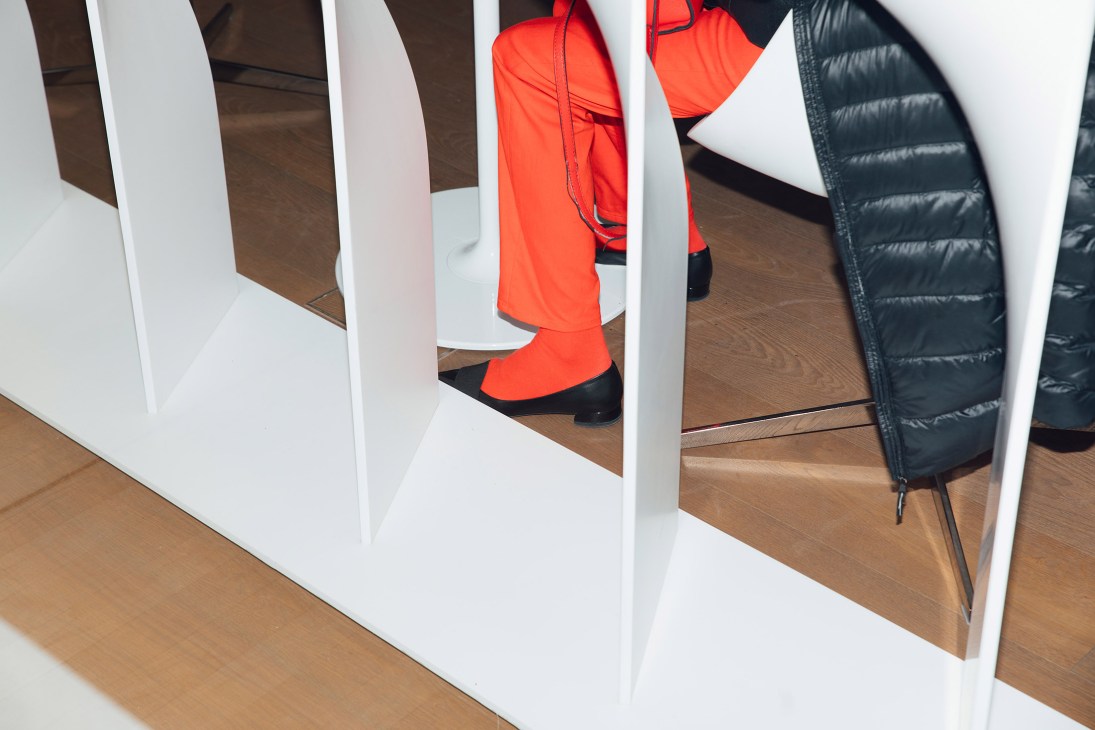 Red and black puffer jackets displayed on white mannequins at a trade show stand.