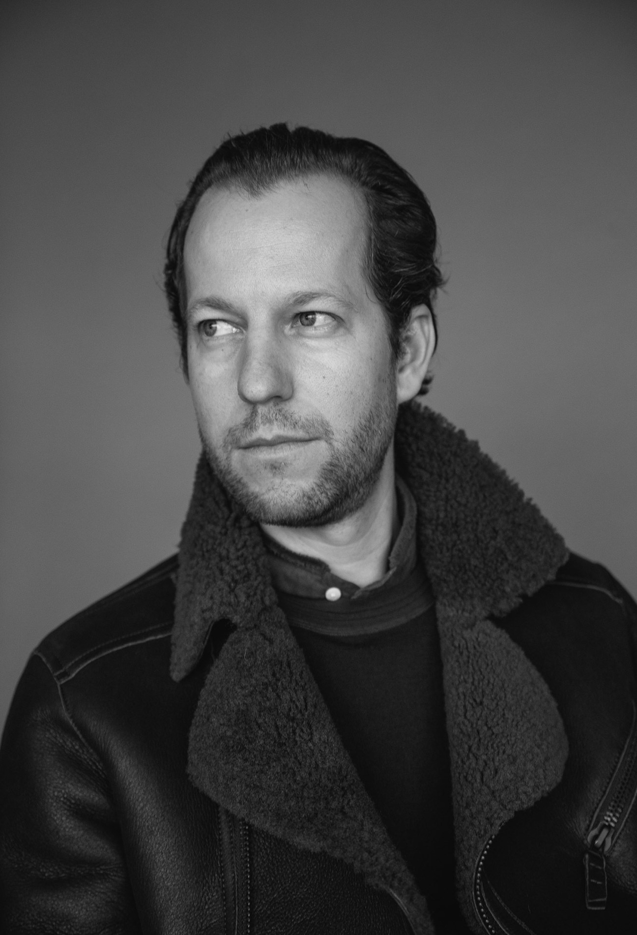 Black and white portrait of Nico Pesko, owner of Pesko in Lenzerheide, wearing a dark jacket with a textured collar.