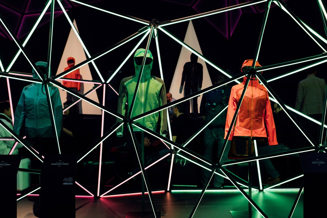 Black Yak sportswear display with mannequins wearing colorful jackets under neon geometric framework lighting.