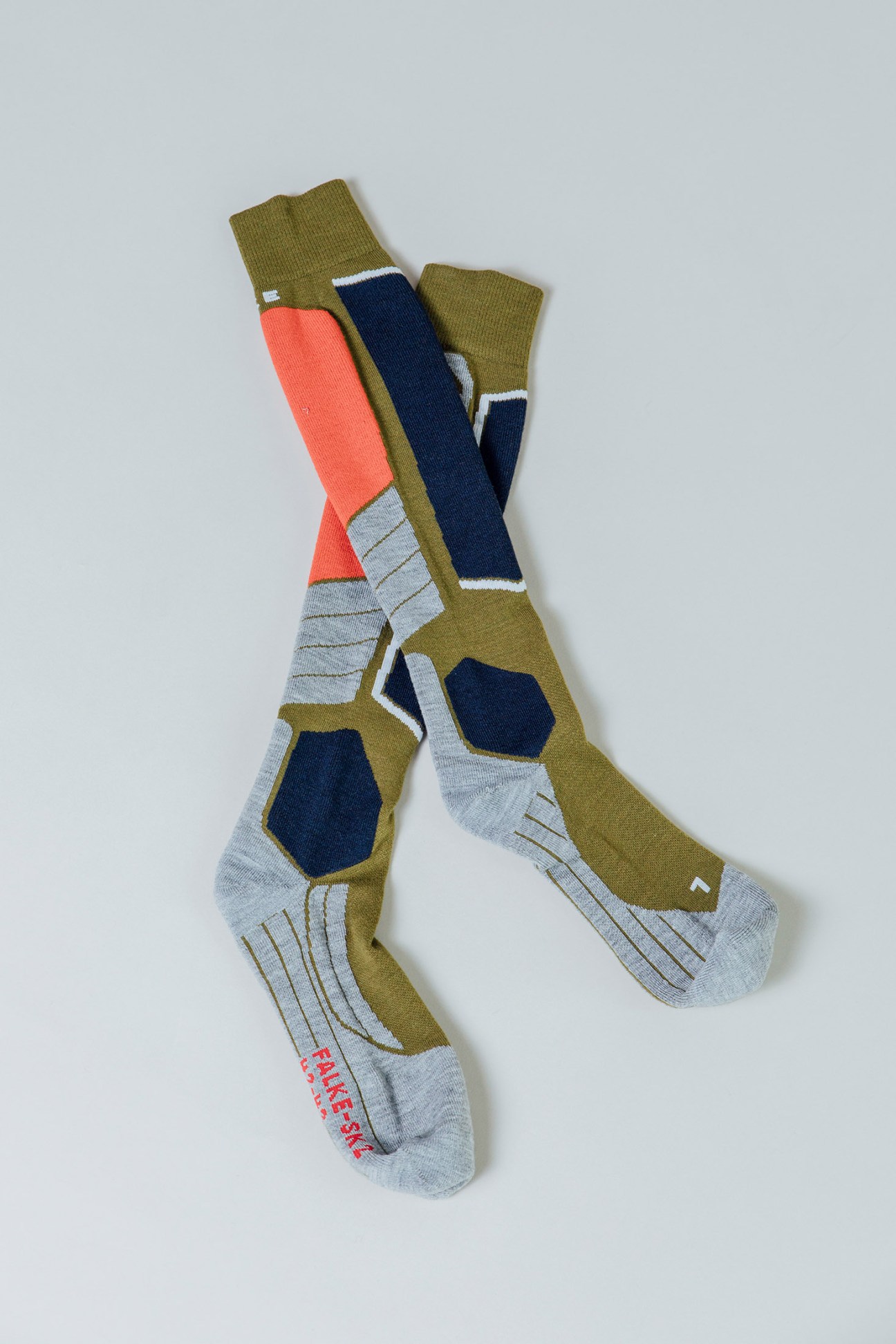 Three colorful Falke performance socks with olive, coral, navy, and gray color blocking and ribbed calf sections.