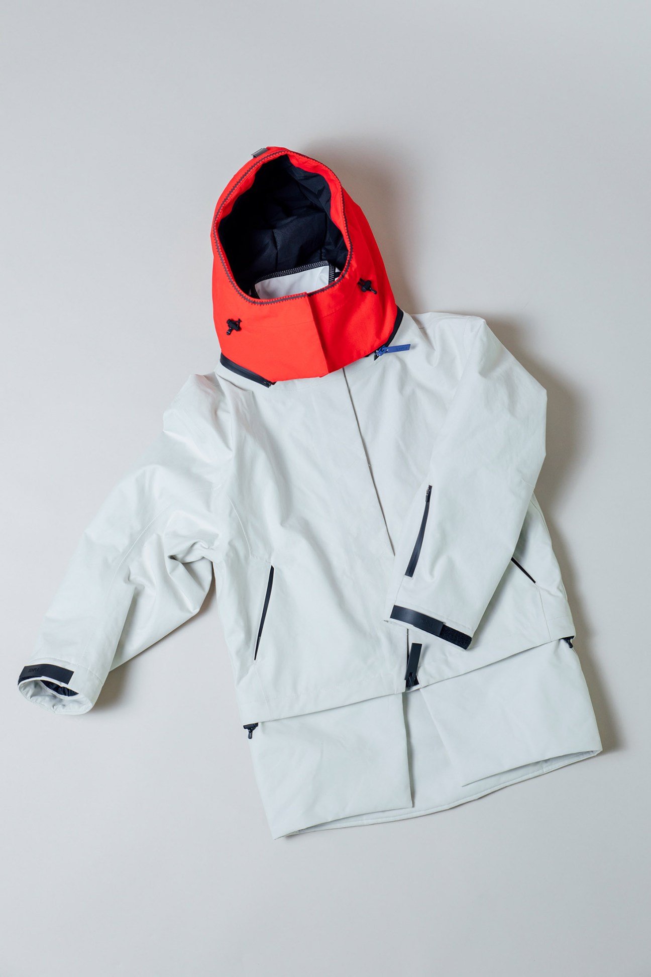 White oversized parka with red hood by Templa displayed flat against white background.
