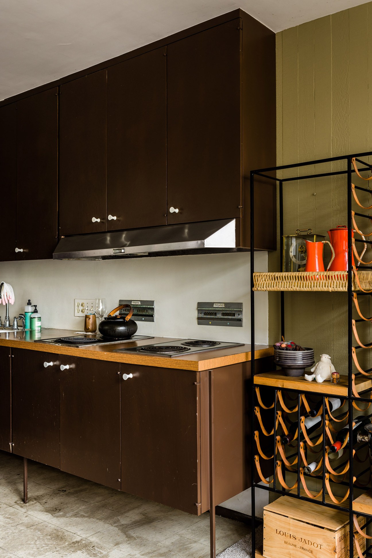 Mid-century modern kitchen with black cabinetry, wood countertop, and olive-green wallpaper.