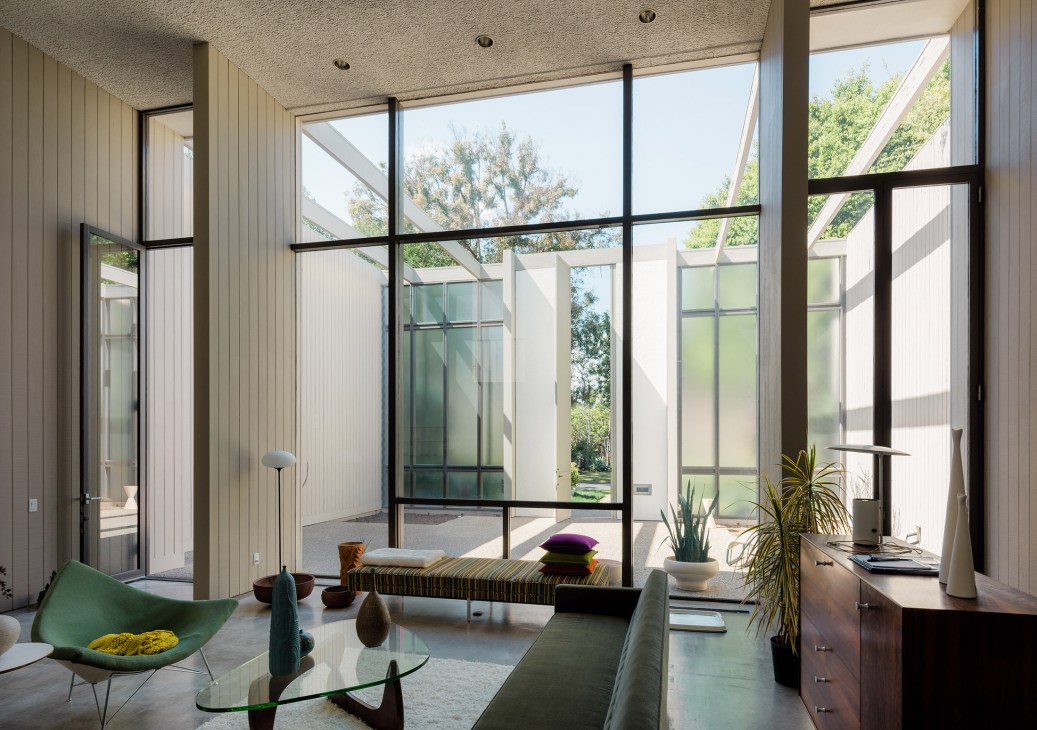 Mid-century modern living room with floor-to-ceiling windows, Noguchi coffee table, and green chair overlooking garden