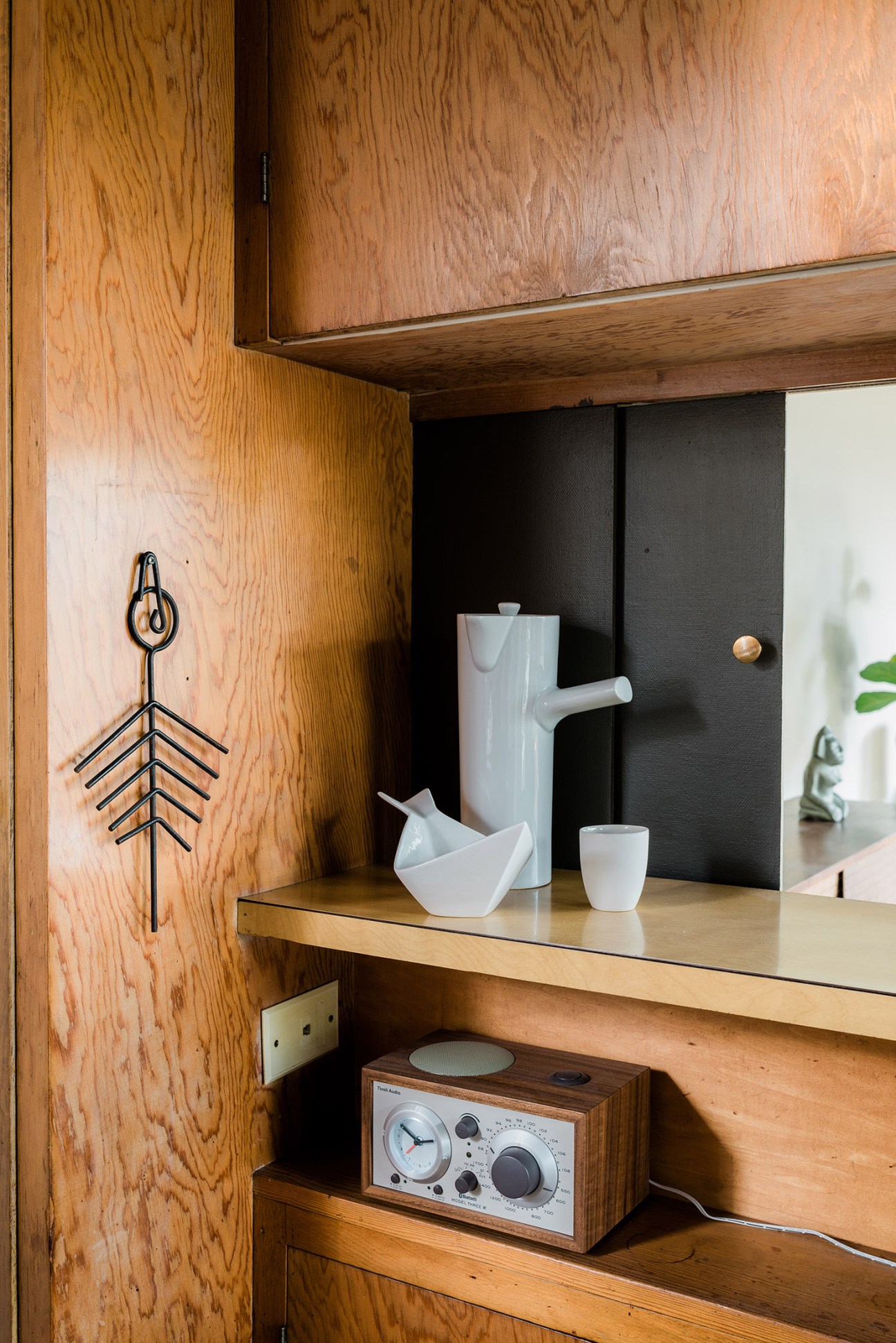 Mid-century modern wooden kitchen shelving with white ceramic vessels and vintage radio.