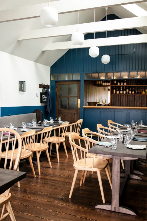 Dining room at the Kinneuchar Inn with wooden chairs, tables set with glassware, and blue-painted walls.