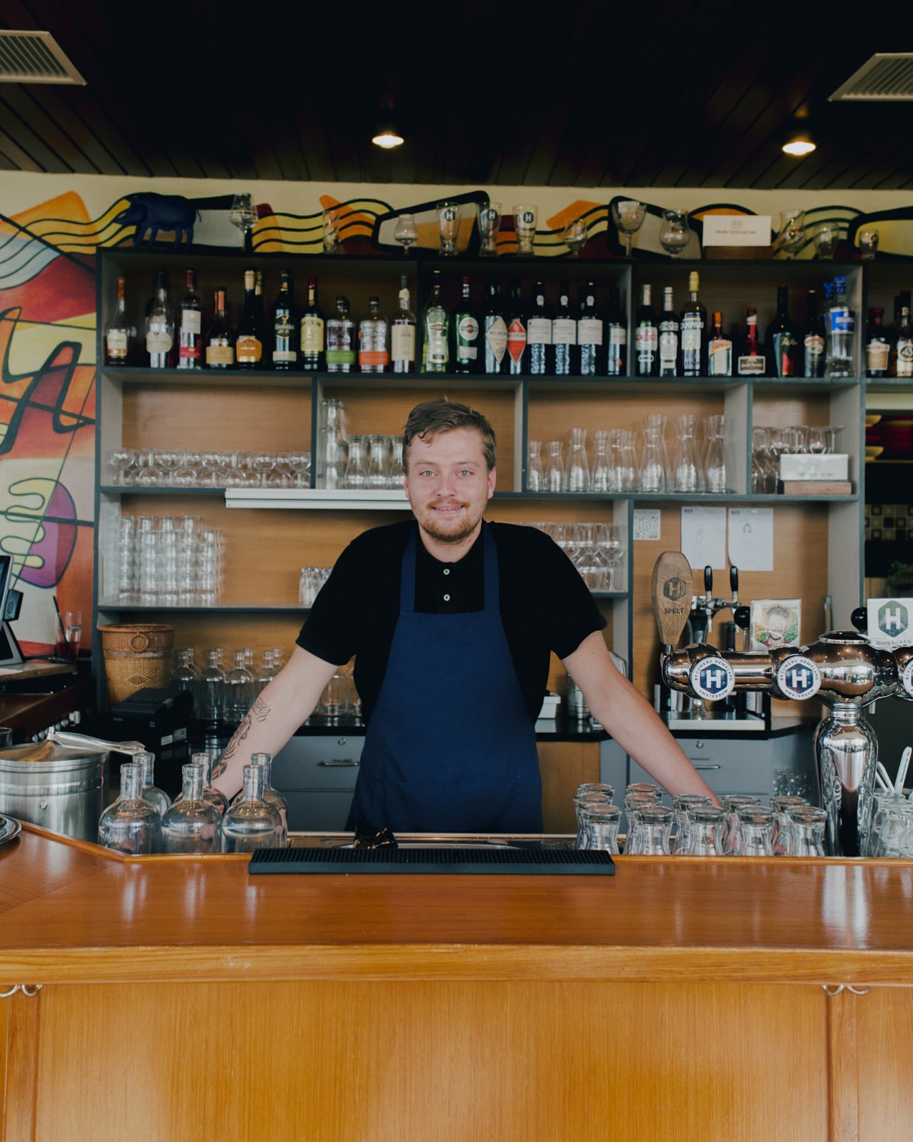 Brewery bartender Erik Spratte at Homeland Brewery bar counter with spirits and glassware.