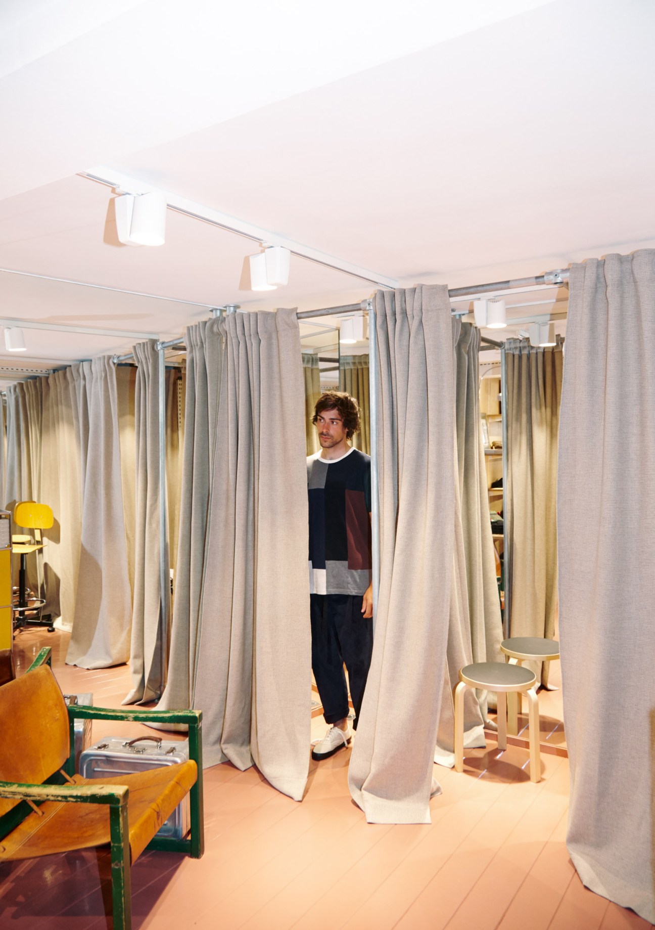 Man standing in a modern changing room with gray fabric curtains and wooden flooring
