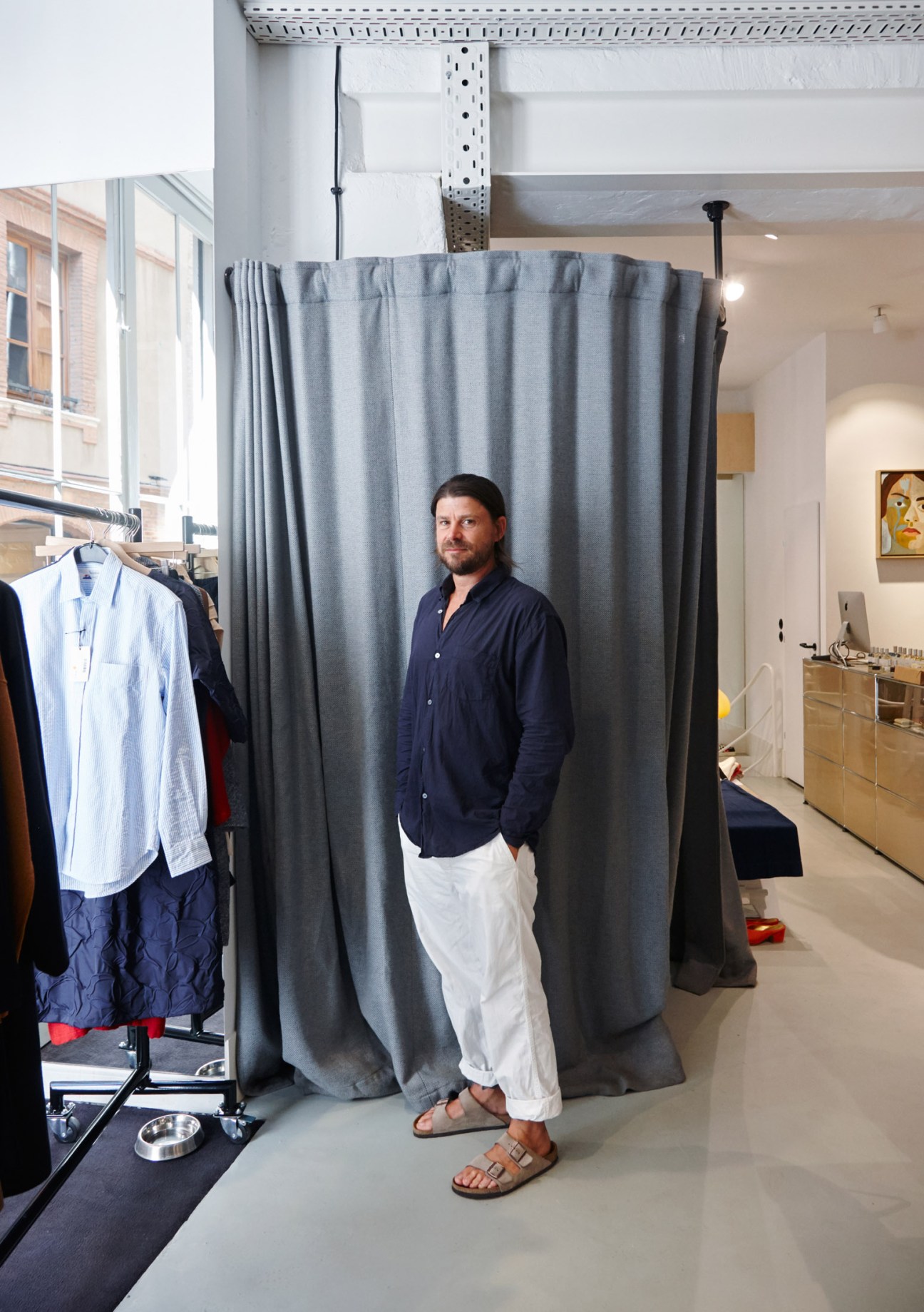 Marc Llorens stands in the womenswear shop among clothing displays and gray curtains.