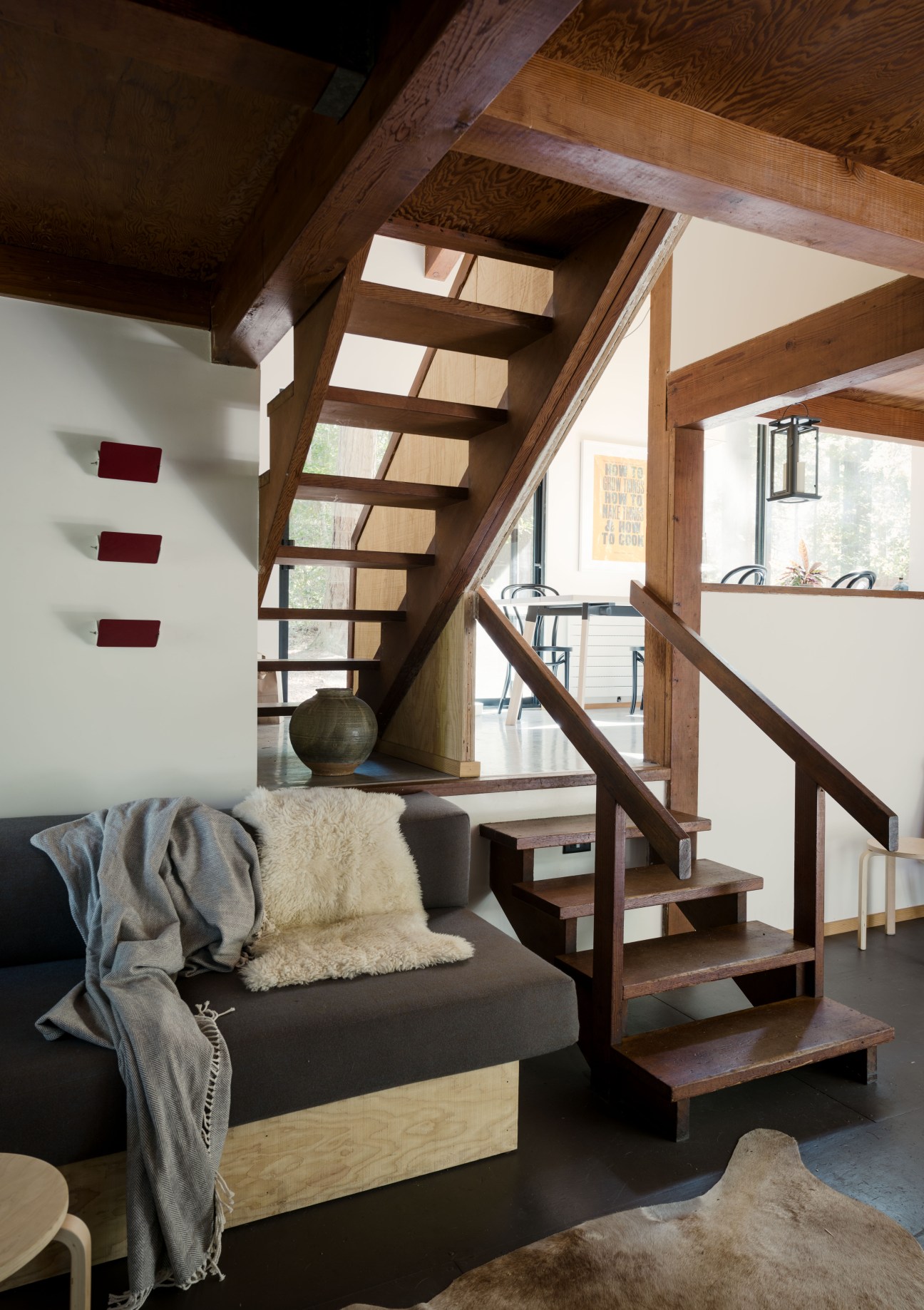 Minimalist wooden interior with staircase, dark sofa, and skylights at Chad DeWitt's Sea Ranch home.