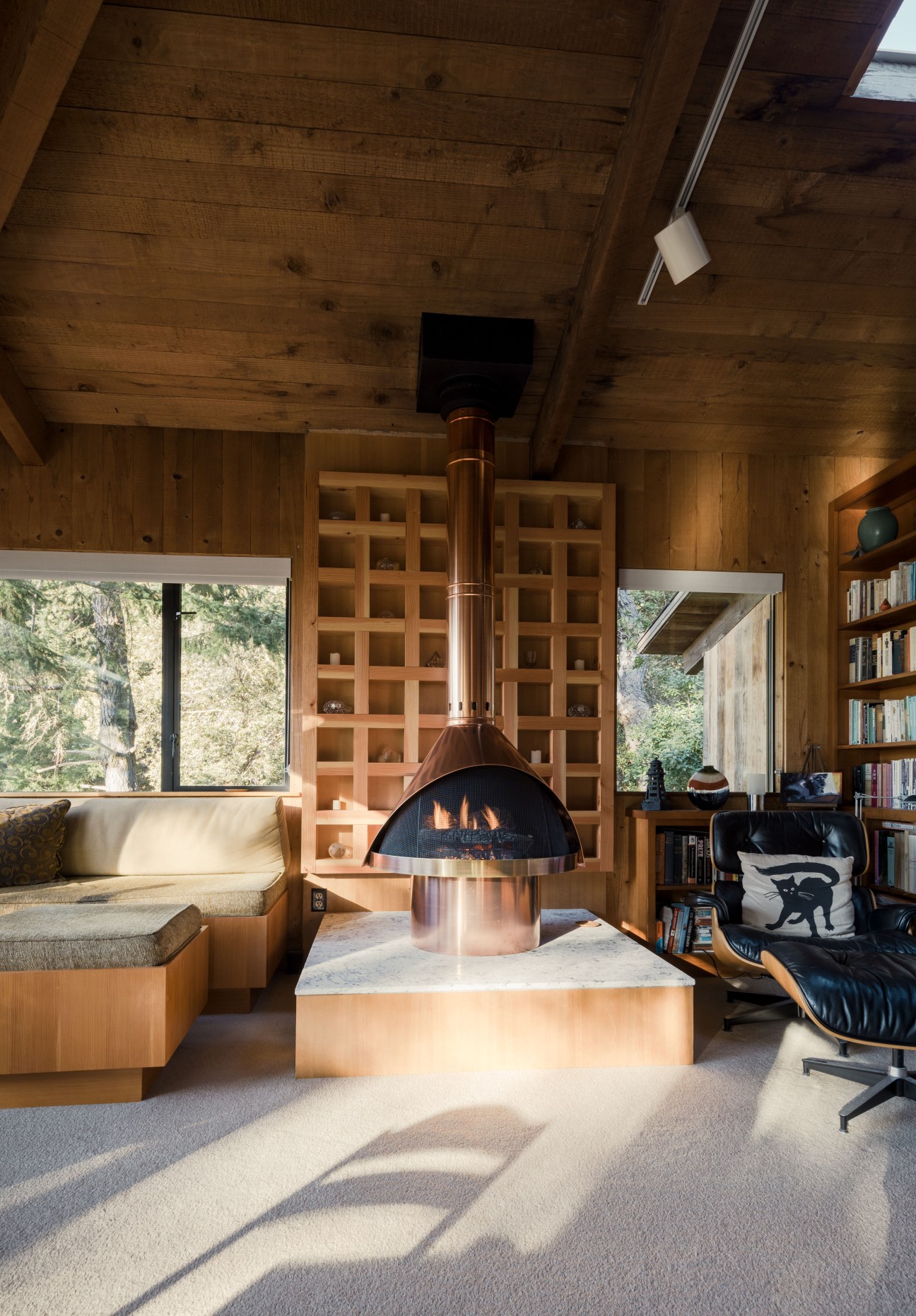 Interior of Peter Jenny's Sea Ranch home featuring a Malm gas fireplace, built-in wooden shelving, and mid-century furniture.