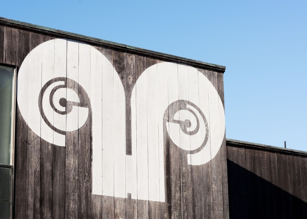 The Sea Ranch community's distinctive white ram's head logo painted on dark wooden siding.