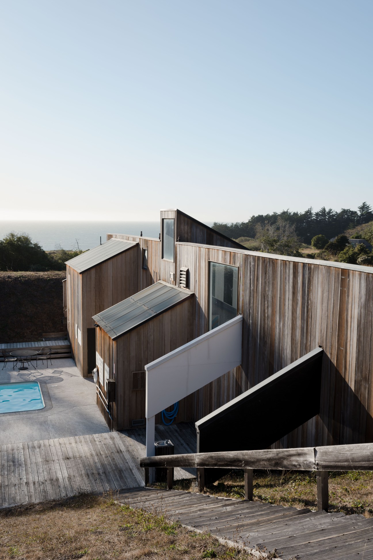 Moonraker pool building featuring characteristic saddle-shaped architectural extensions in weathered wood with ocean views