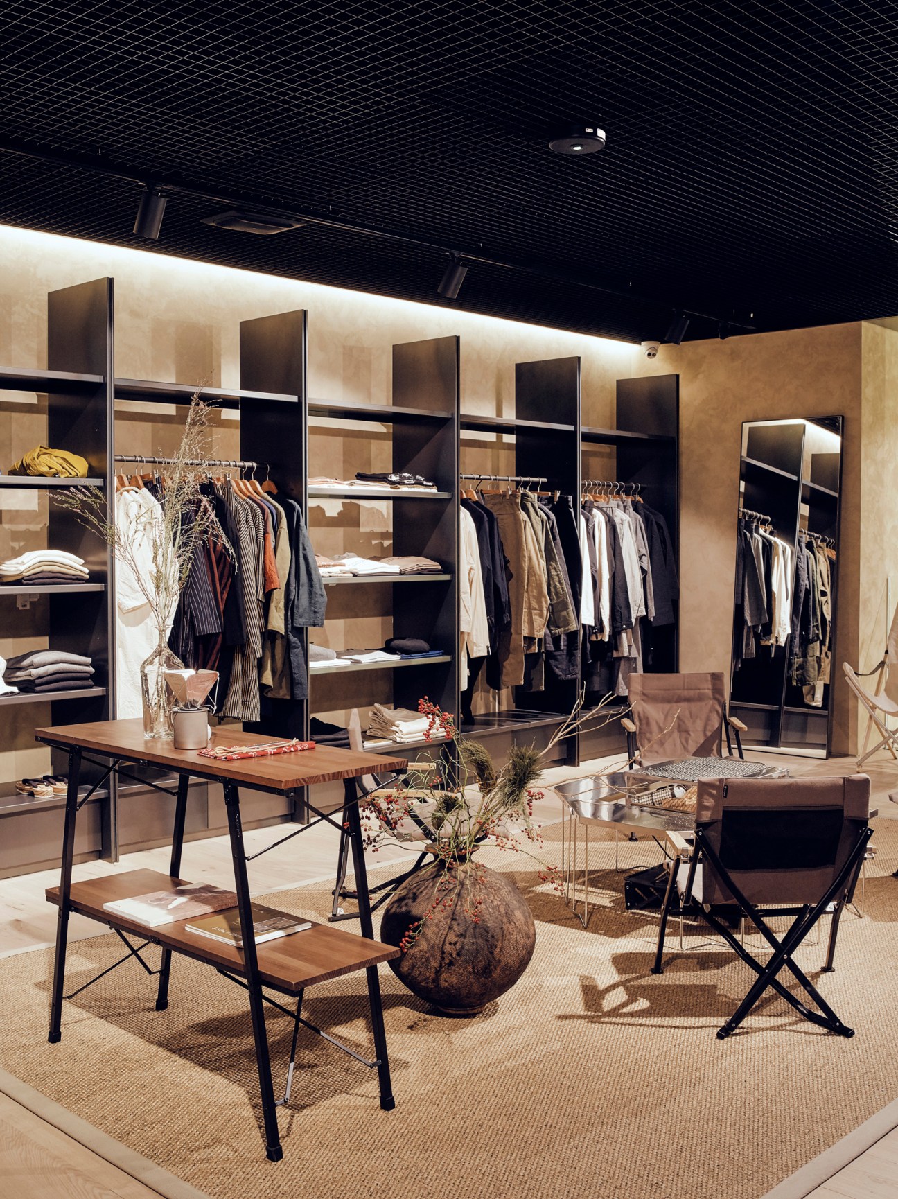 Snow Peak London store interior with clothing displays, shelving units, and central seating area with wooden table