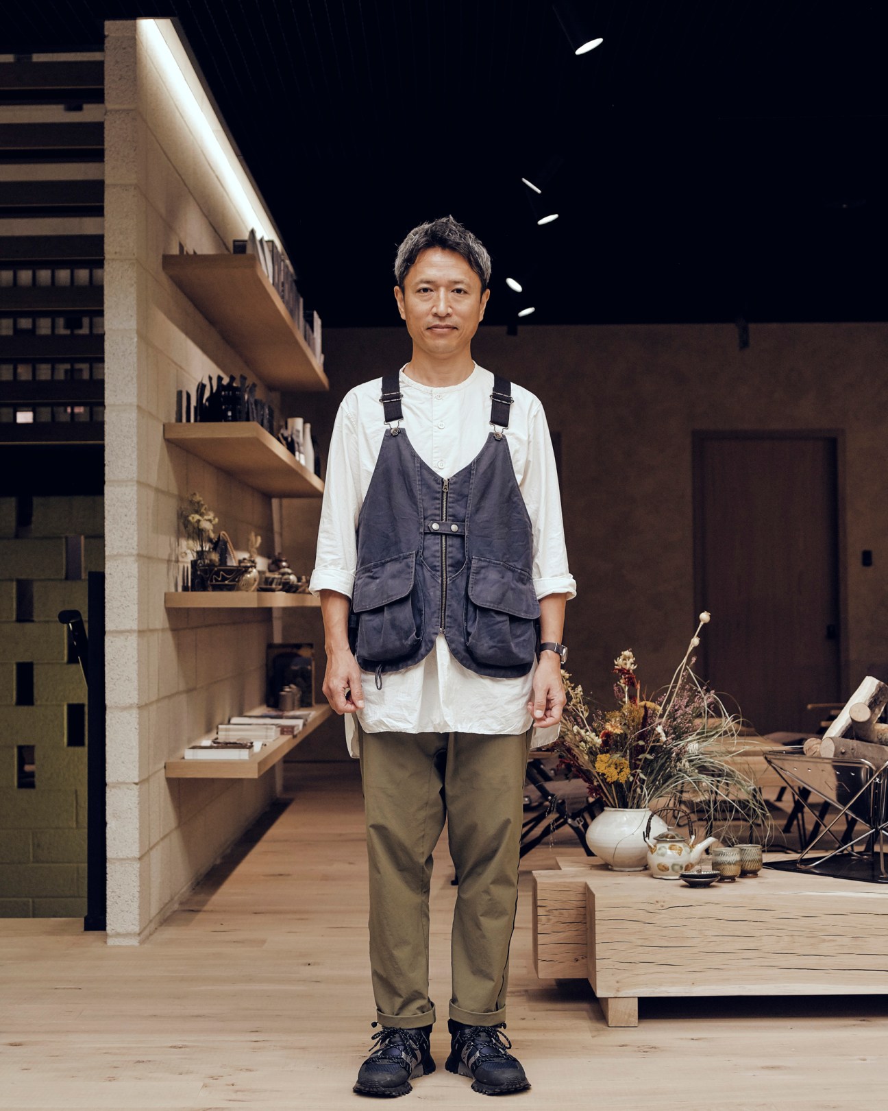 Kei Saito wearing Snow Peak's multi-pocket takibi vest over white shirt in modern store interior