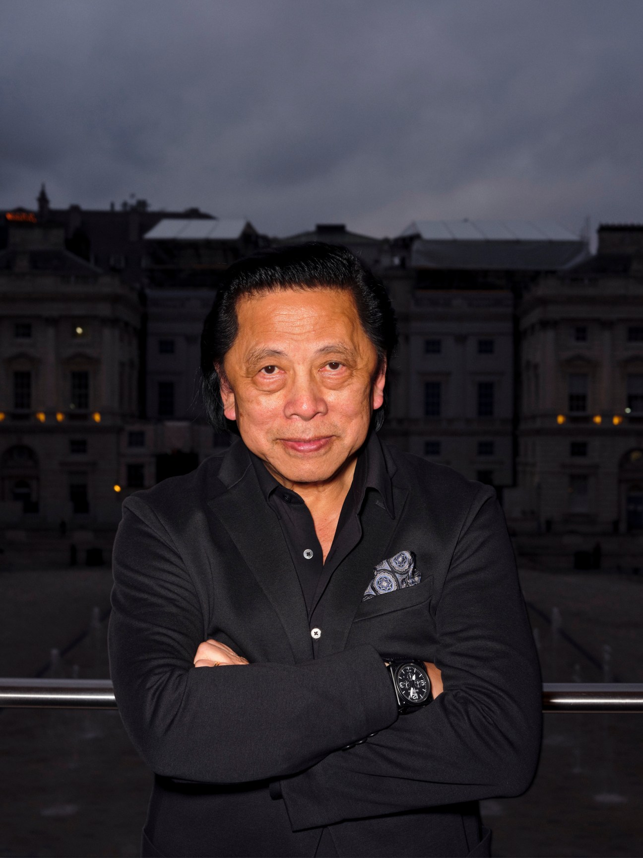 John C Jay standing with arms crossed in front of a historic building at dusk