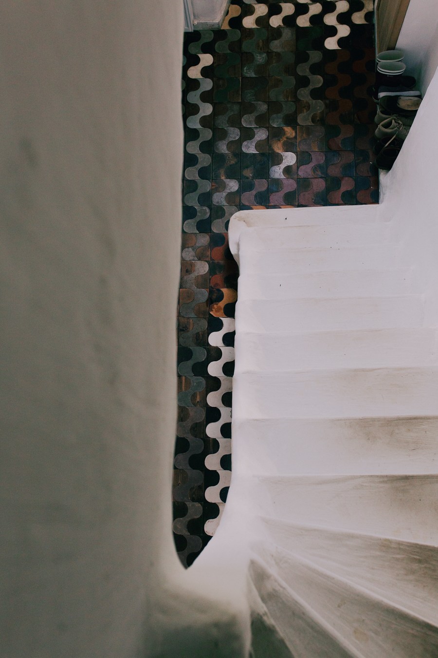 Custom patterned flooring with wavy black and white design next to light wooden stairs.