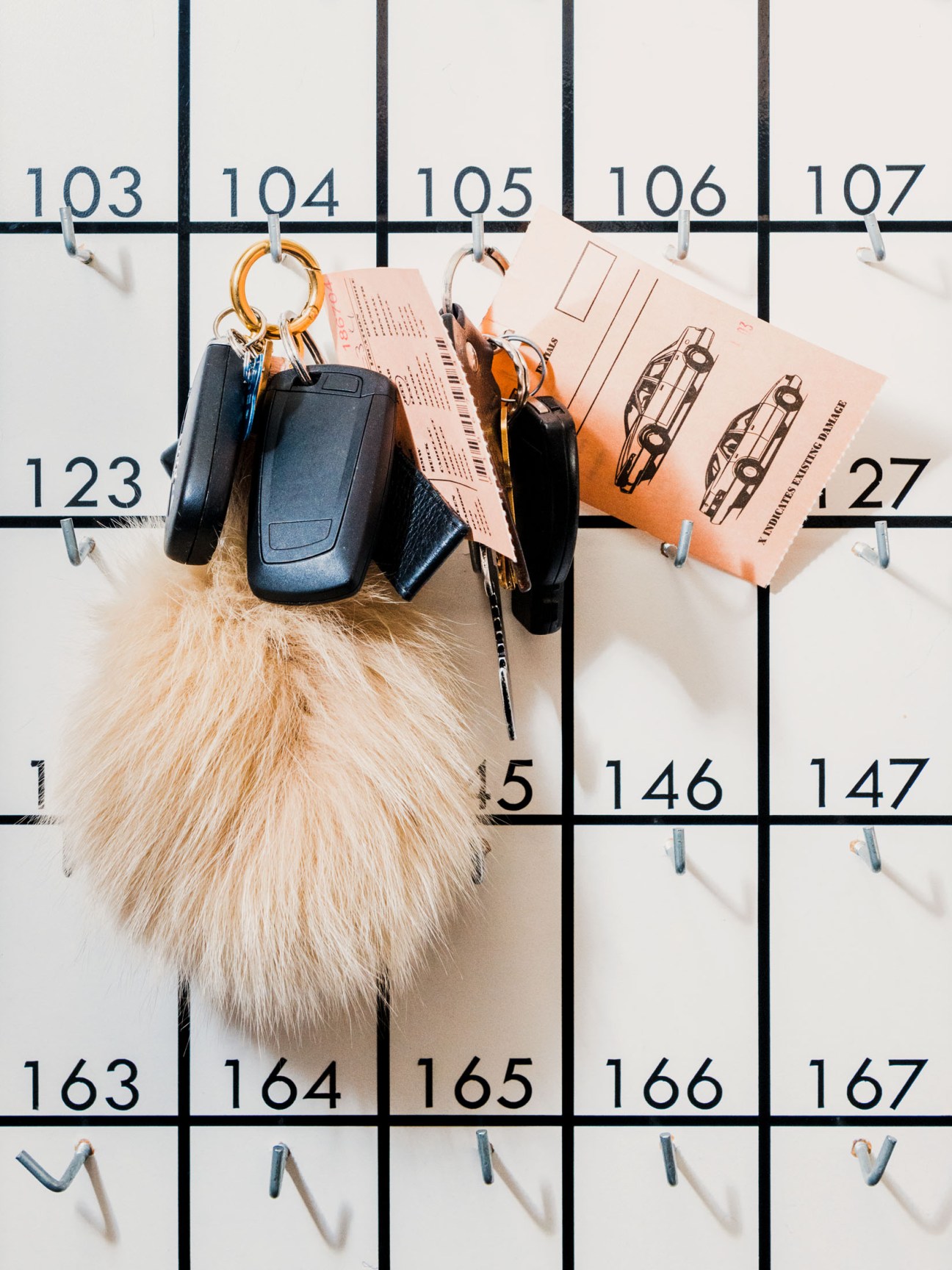 Car keys with numbered tags and keychains hanging on a numbered parking board at The Standard, Hollywood.