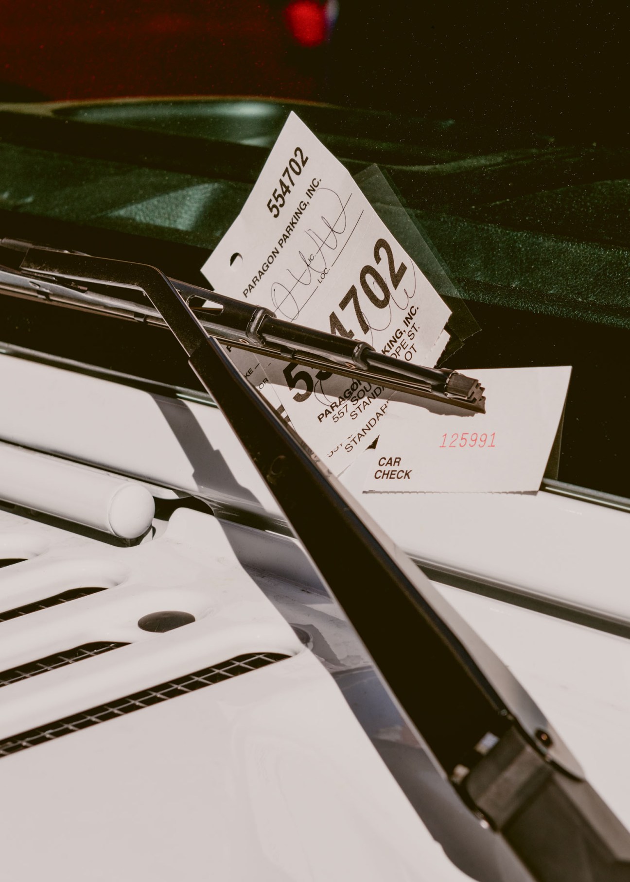 Valet parking tickets clipped to a car's windshield wiper blade.