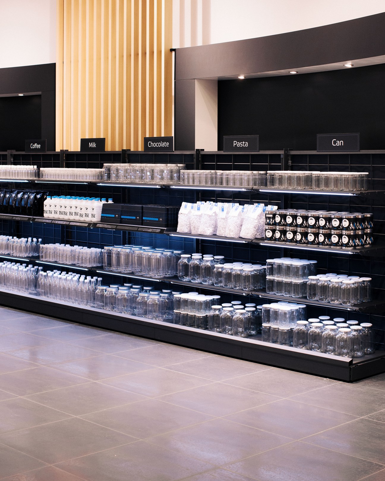 Modern retail shelving display with organized products and category labels in Wanzl's demonstration store