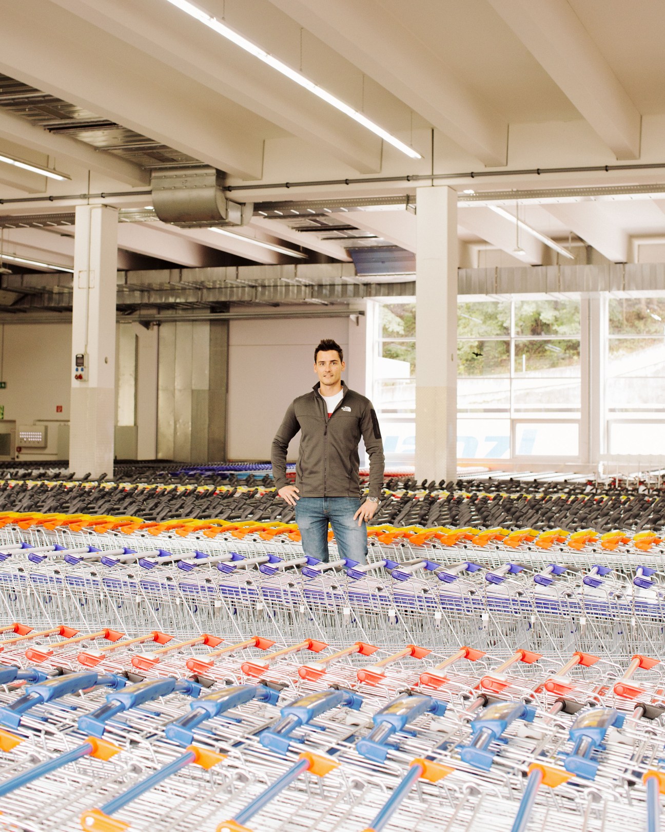Christian Remmele, head of dispatching, standing among rows of shopping trolleys in a warehouse facility.