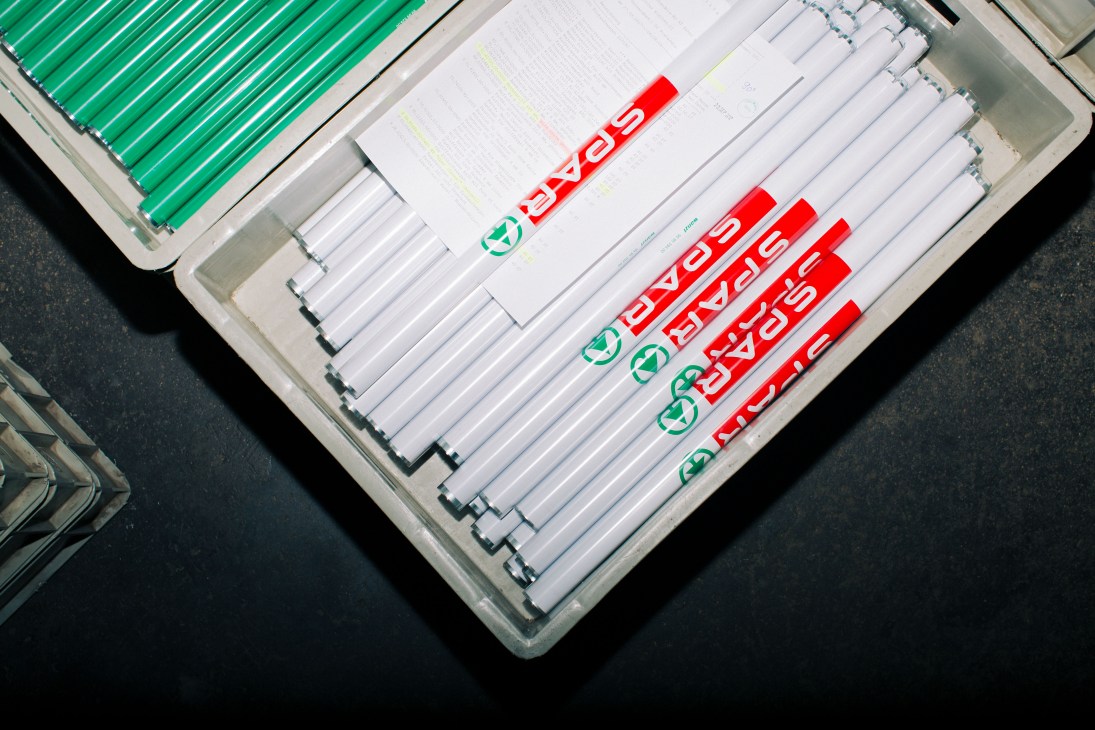 Close-up of shopping trolley handlebar components with Spar branding displayed on factory floor.