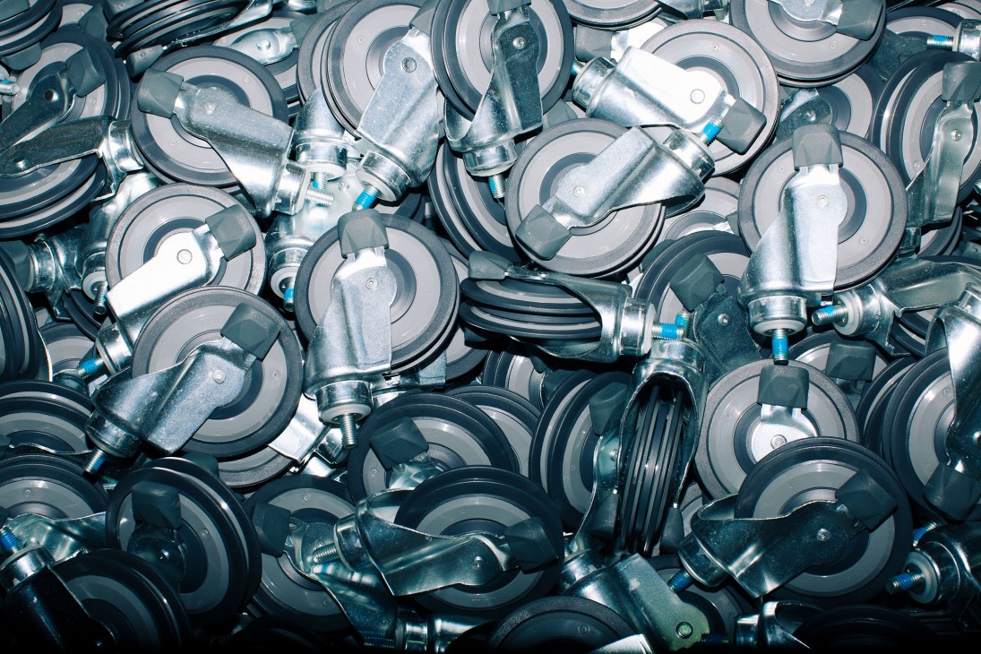 Close-up of metal shopping trolley wheel components with castors and metal brackets arranged together