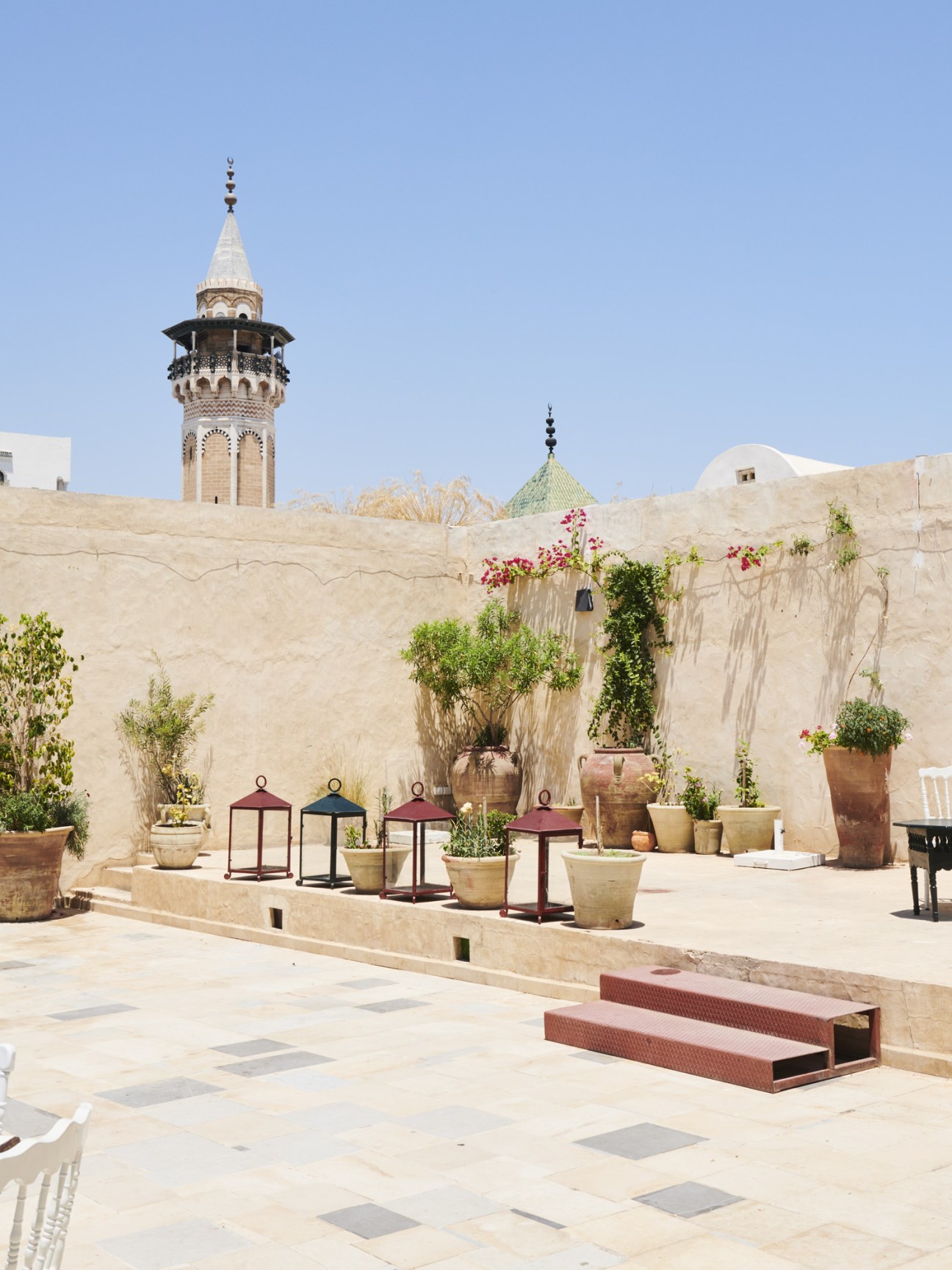 Courtyard at Café M'Rabet in the medina with traditional architecture, lanterns, potted plants and flowers against pale stone walls.
