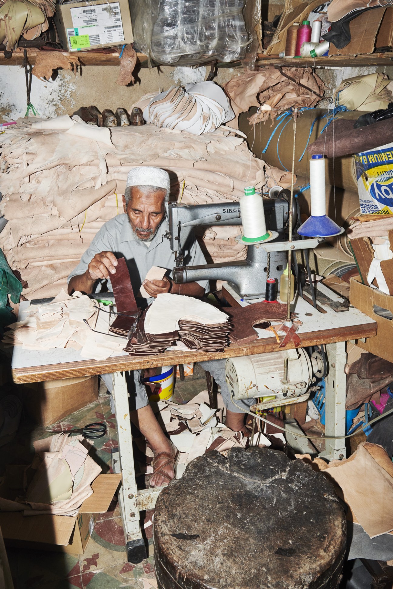 Craftsman Souhail Fitouri making traditional Tunisian balgha slippers at his workbench using leather and hand tools.