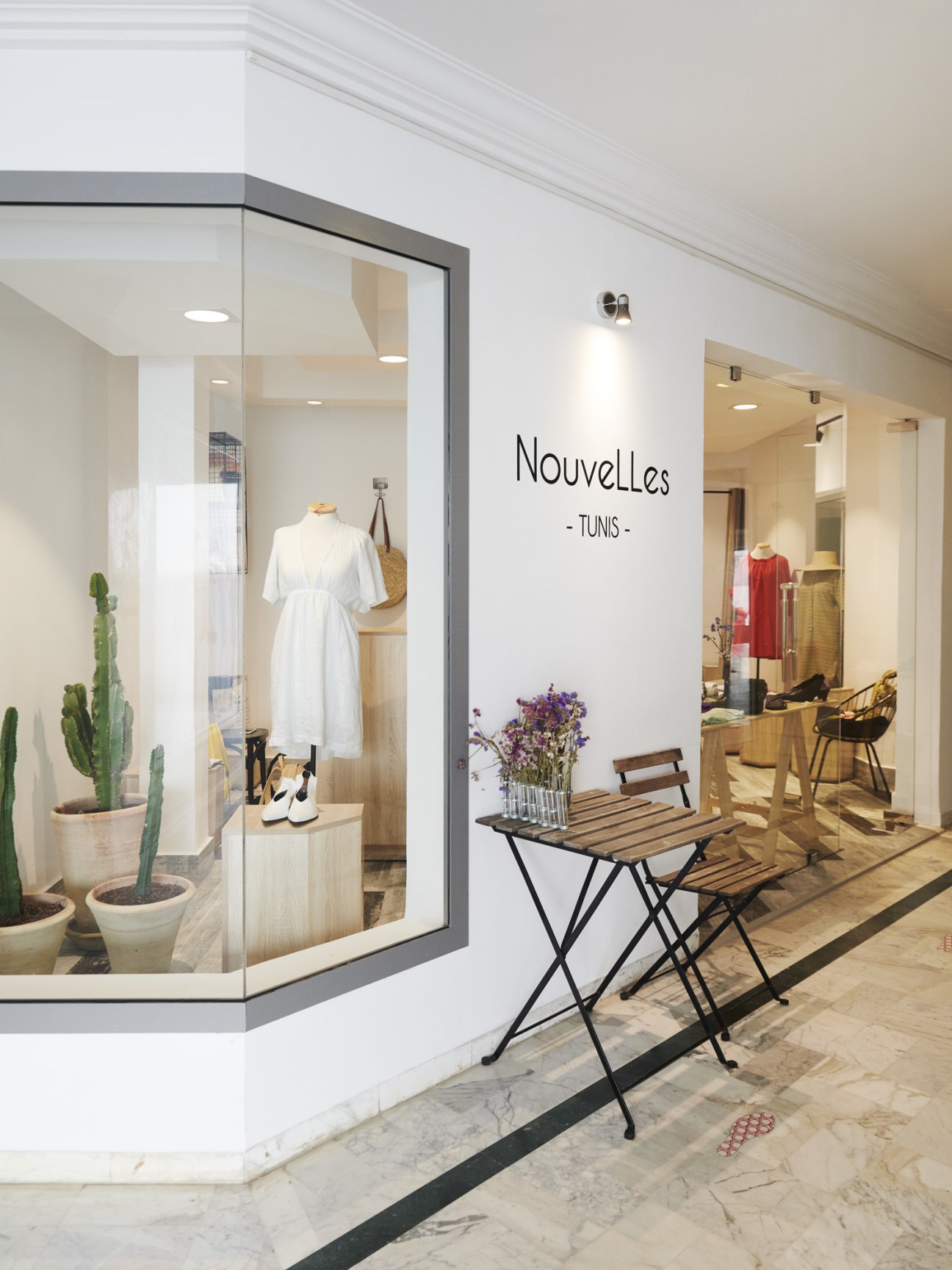 NouvElles Tunis boutique storefront with minimalist design, cacti, and clothing displays visible through glass windows.