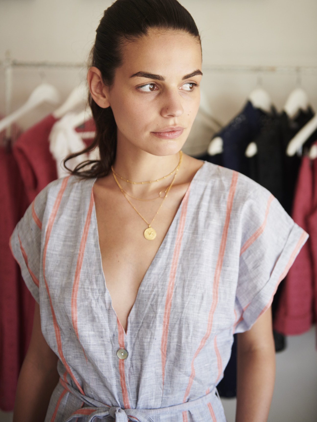 Woman wearing a striped linen dress with coral and white stripes at My Little Bagatelle boutique.