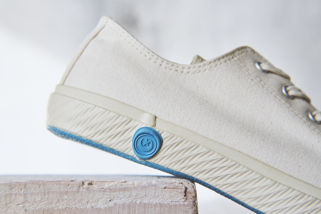 Close-up of Shoes Like Pottery sneaker with cream canvas upper and blue rubber sole.