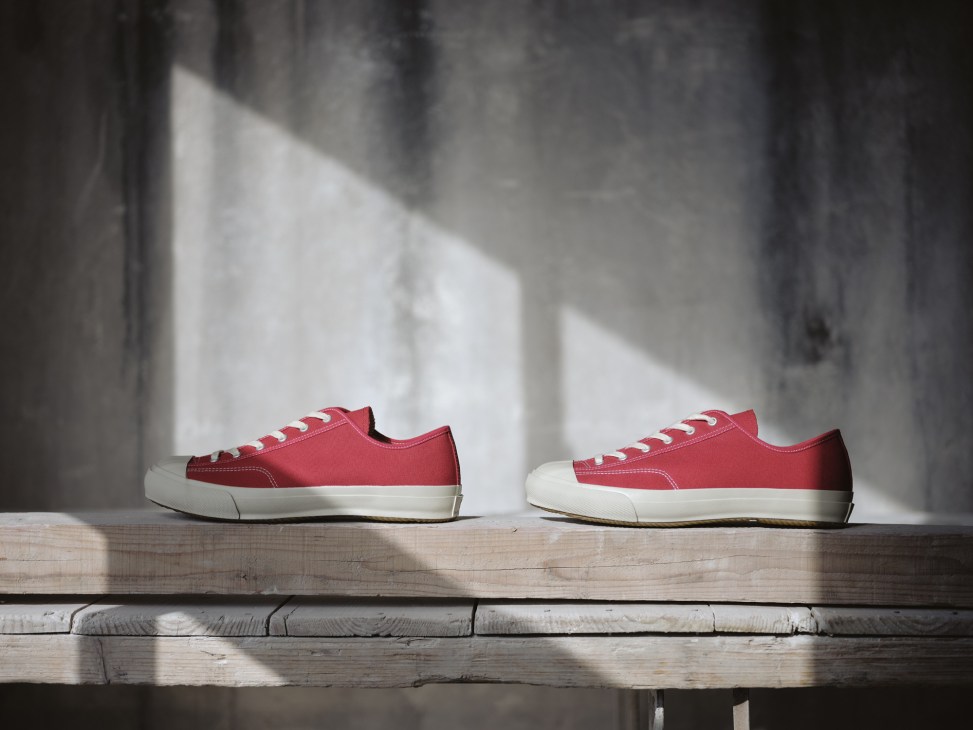 Two red canvas and white rubber Shoes Like Pottery sneakers displayed on wooden shelf in natural light.