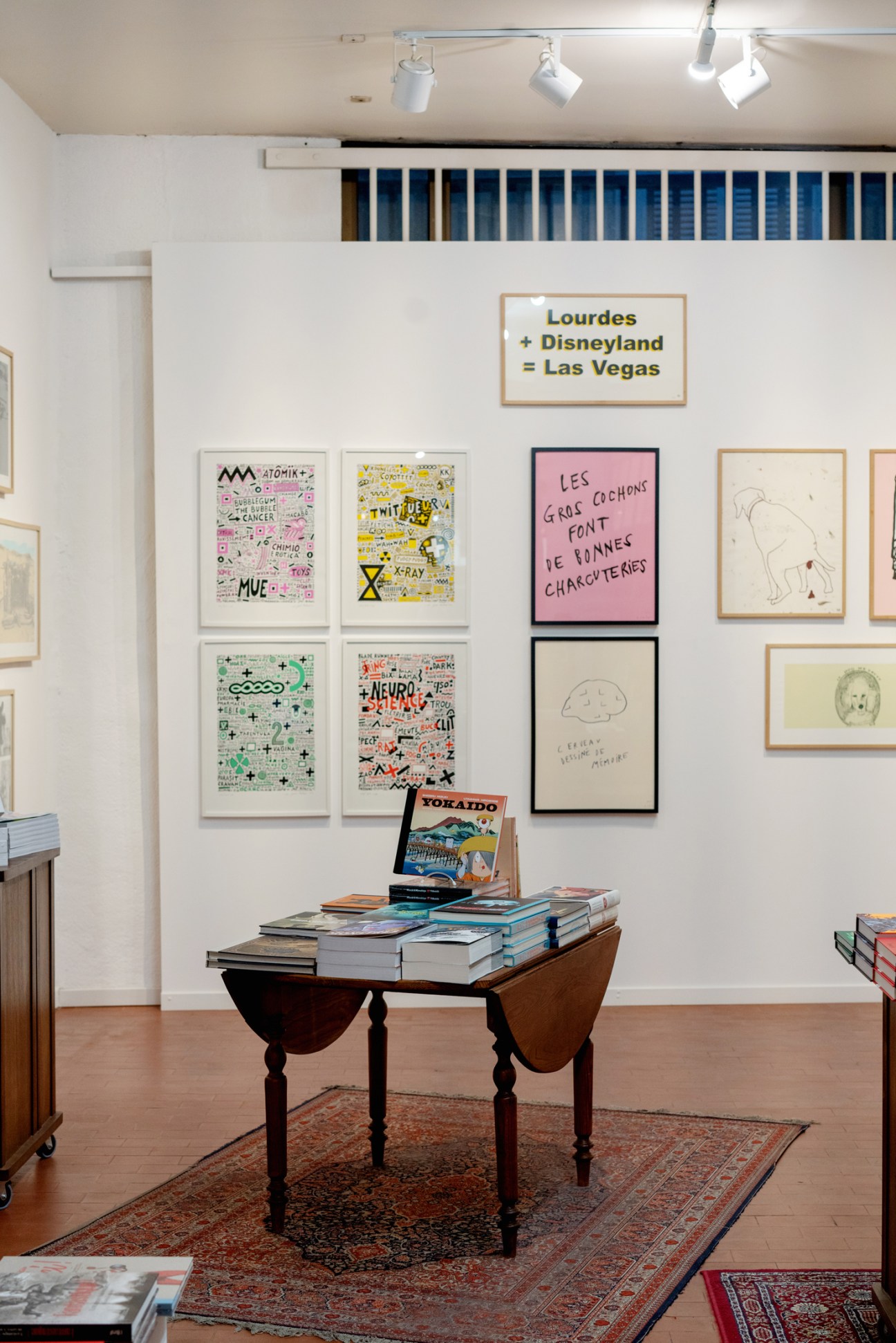 Interior of Bad Reputation bookshop with framed artwork on white walls and books displayed on a wooden table.