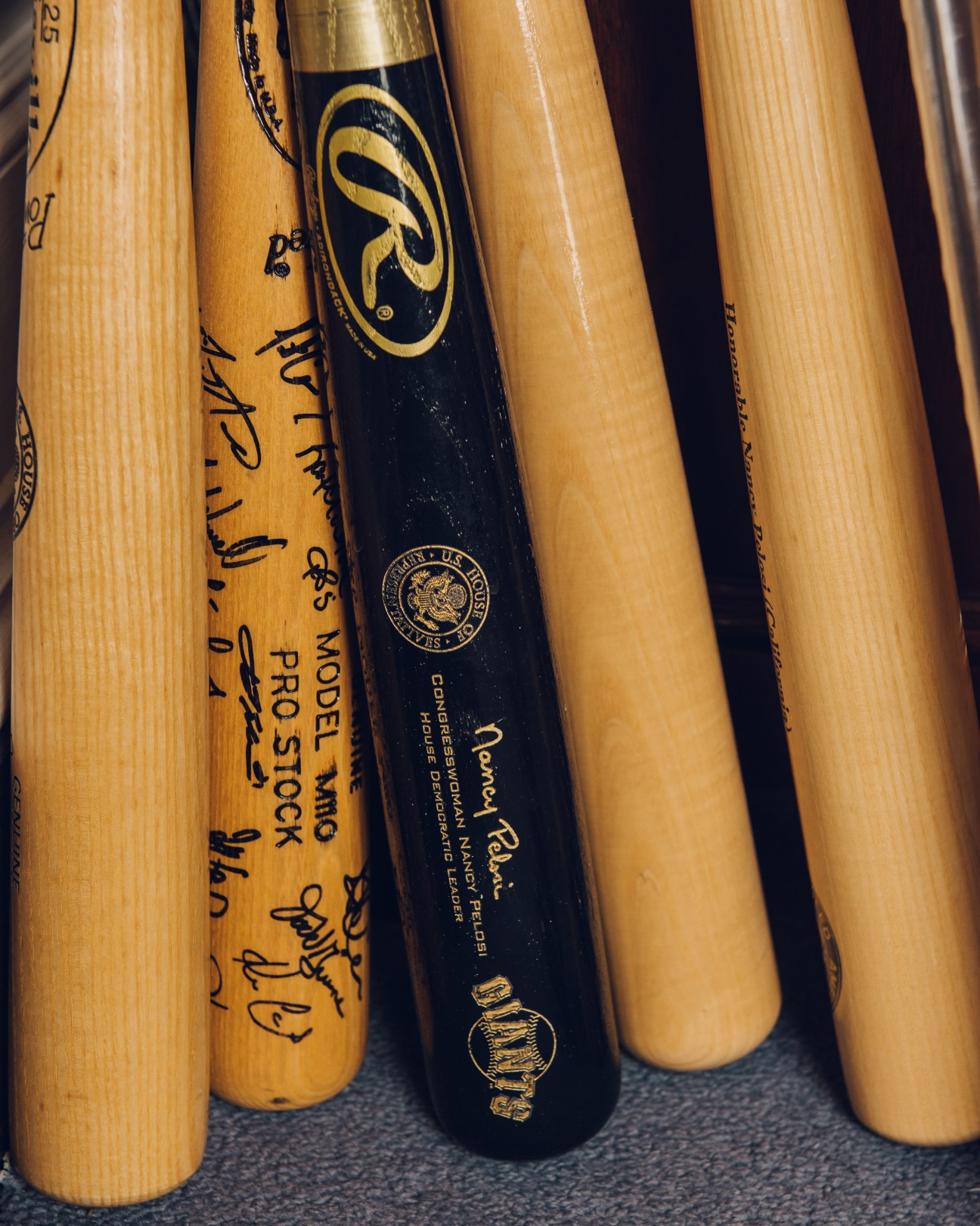 Collection of wooden baseball bats with various brand markings and signatures leaning against each other