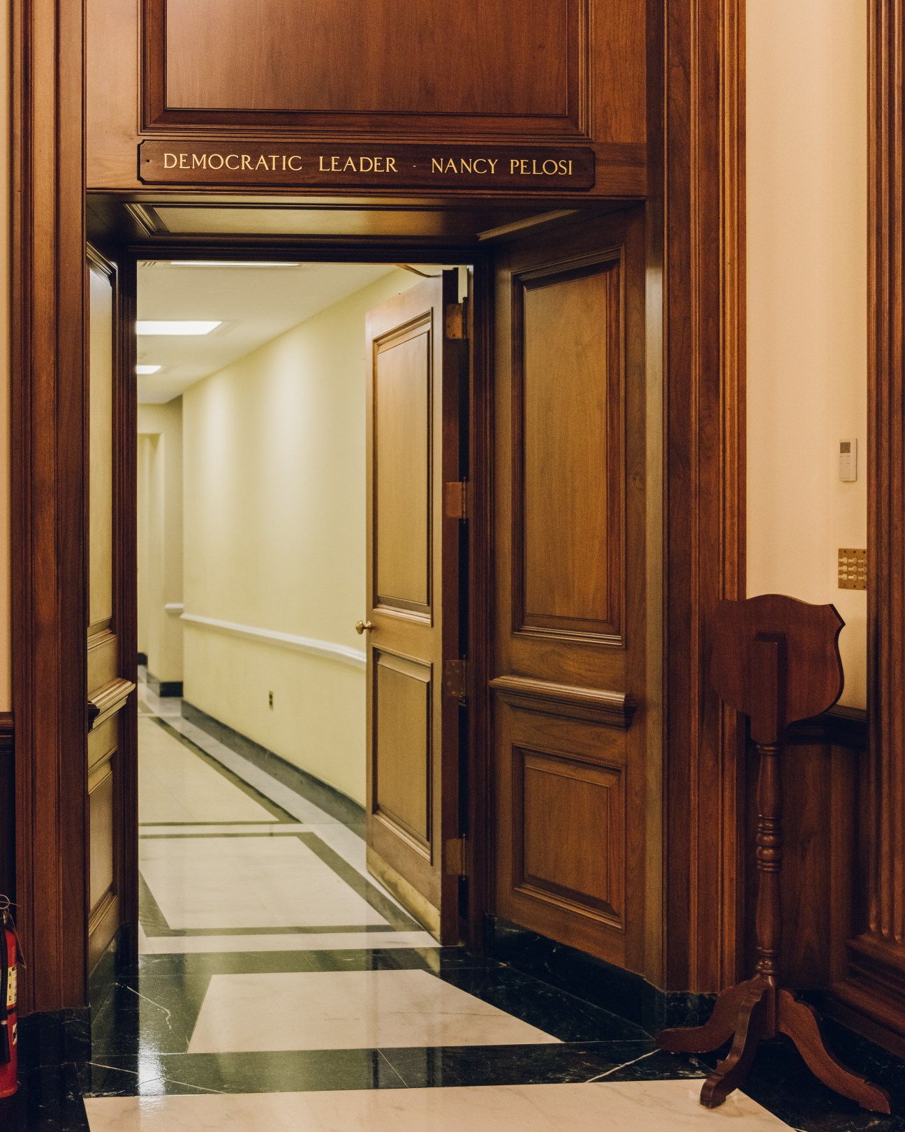 Open wooden double doors with nameplate reading 'Democratic Leader Nancy Pelosi' above the entrance