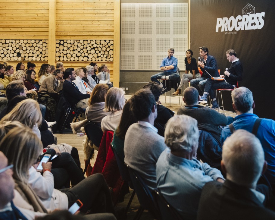 A diverse group of attendees seated in a wooden-walled venue listening to panelists discussing innovation at a Les Napoleons workshop.
