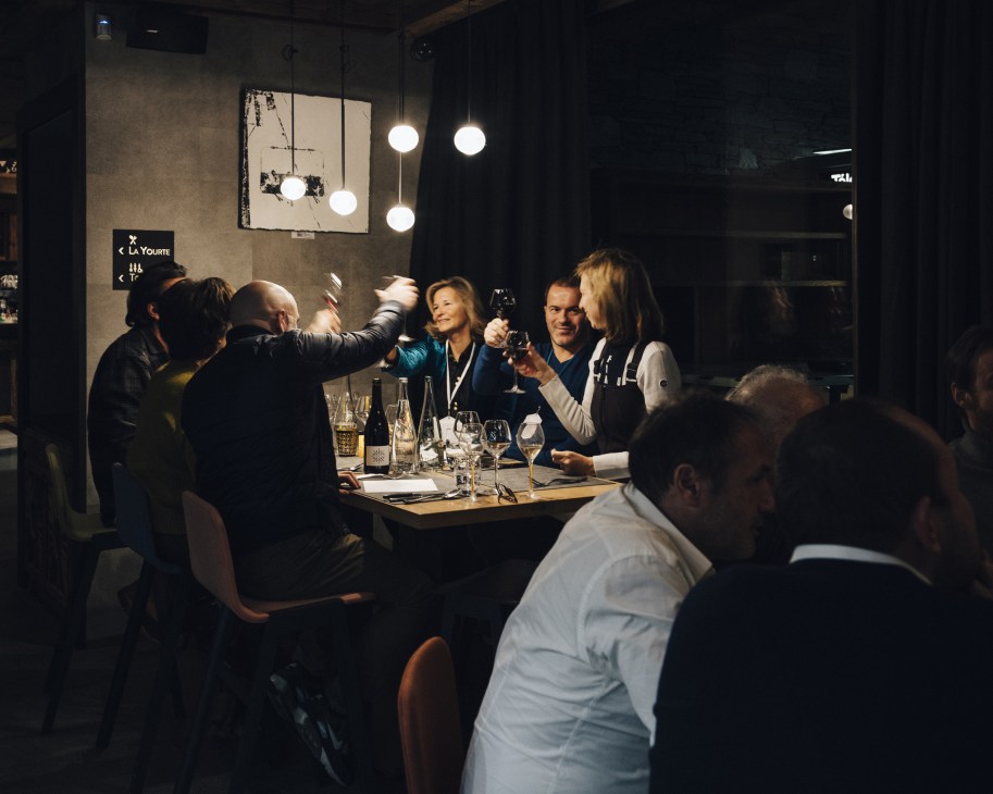 Guests toasting with drinks at a dining table during a Les Napoleons event.