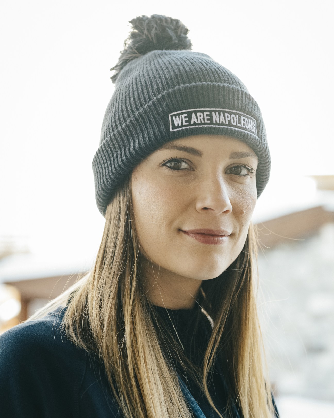 Woman wearing a grey beanie hat with 'We are Napoleons' text printed on it.