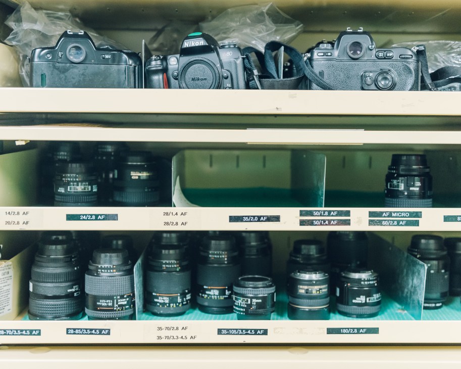 Professional camera equipment and lenses organized on shelves in National Geographic's equipment room.