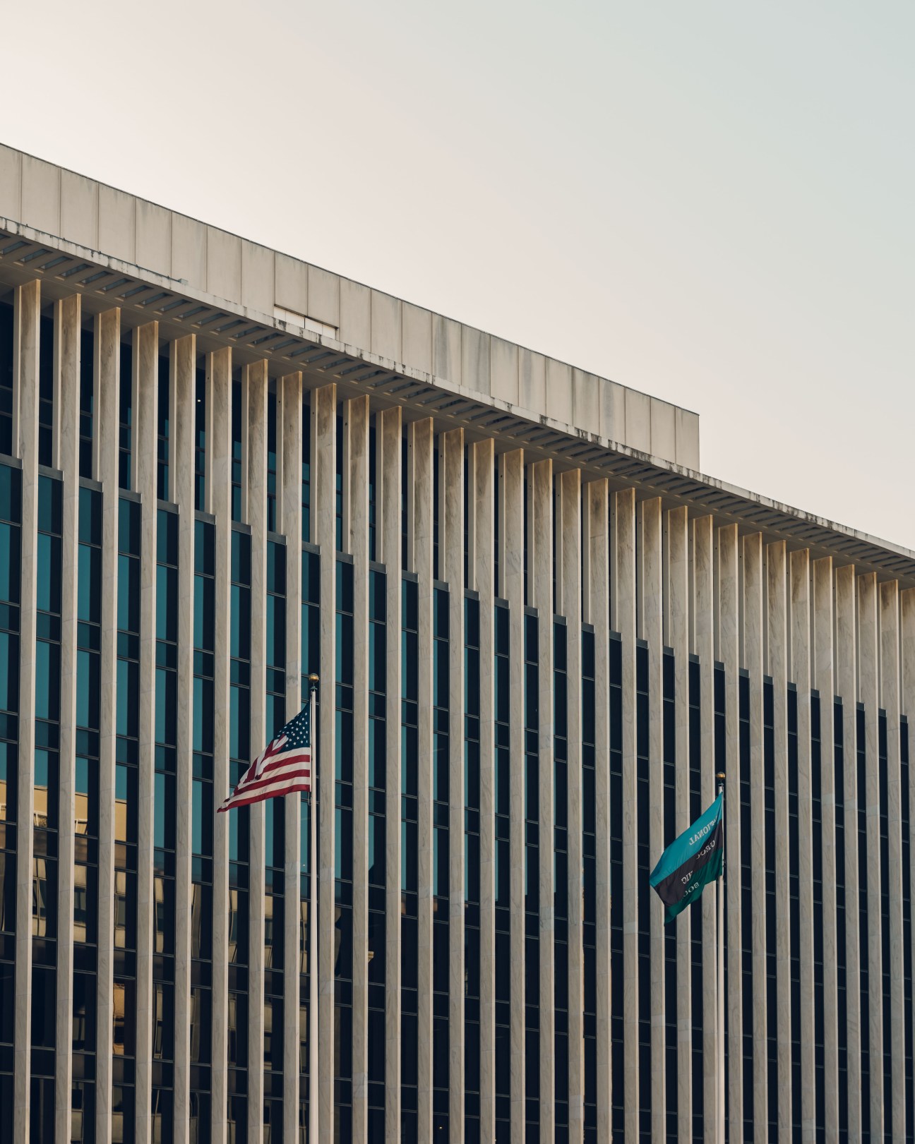 National Geographic Society headquarters building with vertical ribbed facade, American flag and institutional flag displayed.