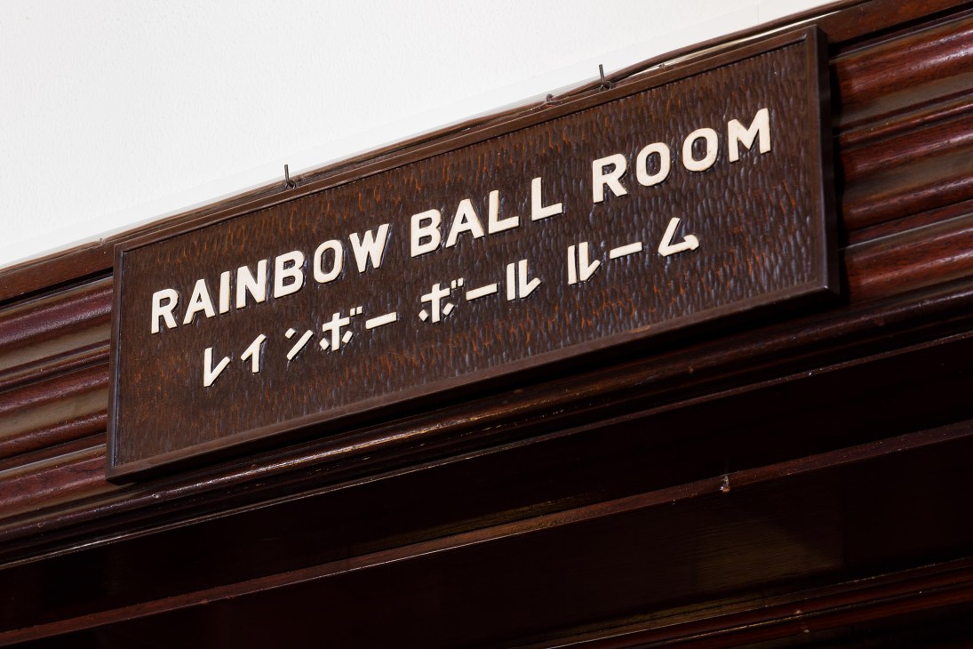 Wooden sign reading 'Rainbow Ball Room' in English and Japanese characters on dark wood paneling.
