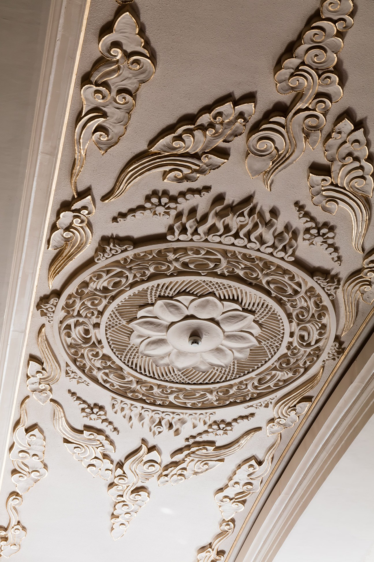 Ornate white plaster ceiling decoration with scrollwork and floral medallion in the Rainbow Ball Room.