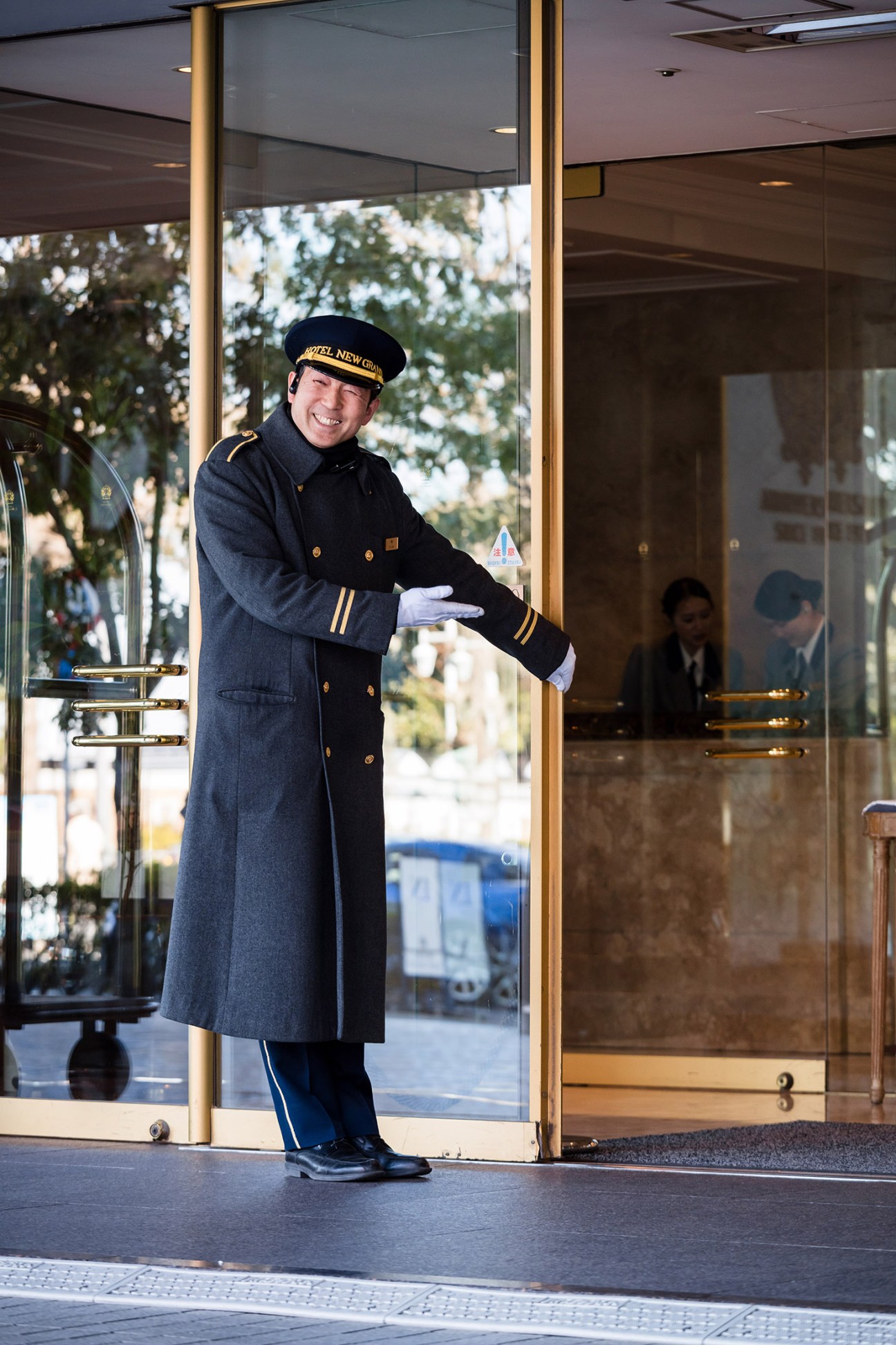 Hotel doorman in uniform welcoming guests at the entrance of Hotel New Grand.