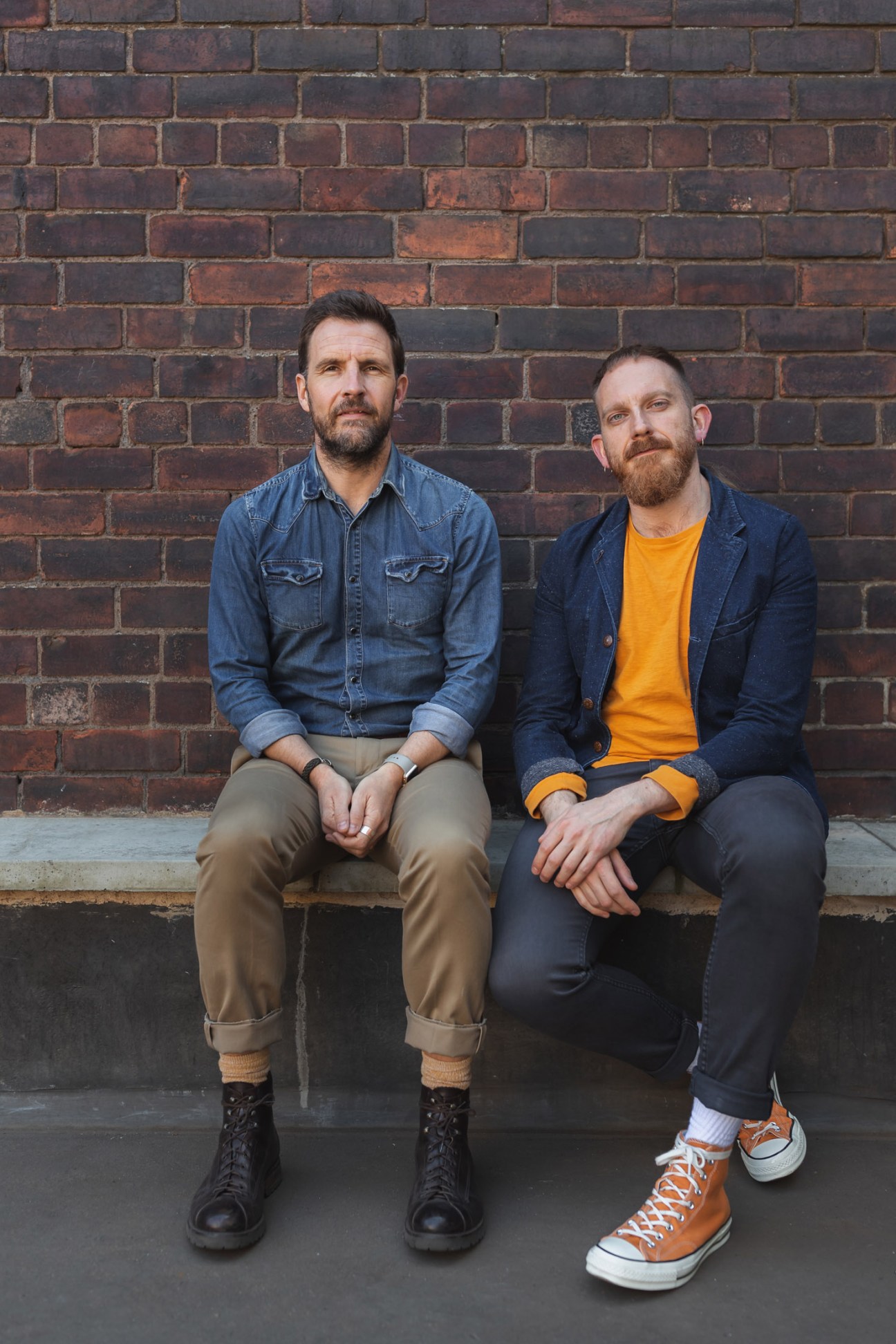 Tim Hubbard and Nick Clark, founders of 93ft design studio, sit against a brick wall.