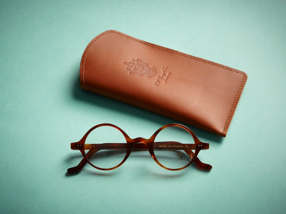 CW Dixey & Son Chartwell 01 spectacles with tortoiseshell frame and leather case on turquoise background.